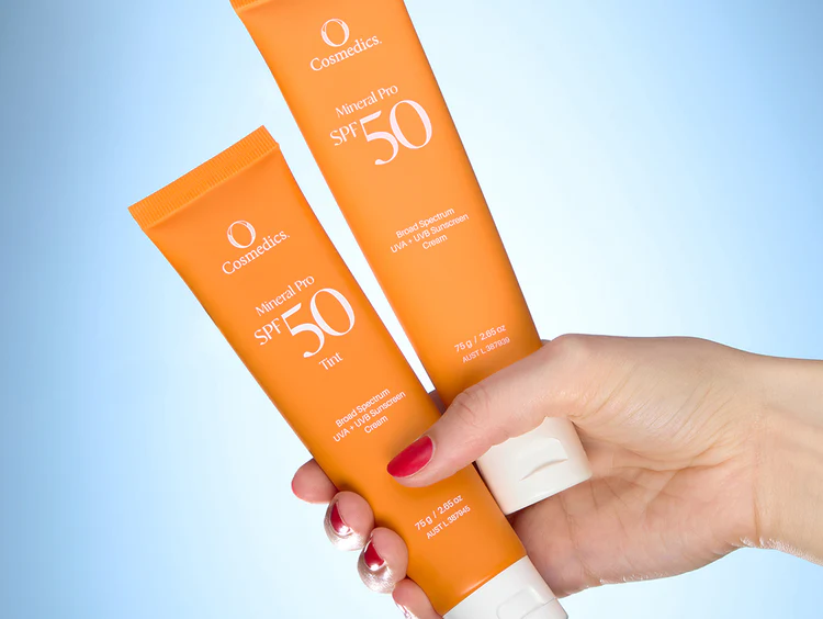 mineral-spf-50-with-light-blue-background A couple of Mineral SPF 50 in tubular packaging held by a lady